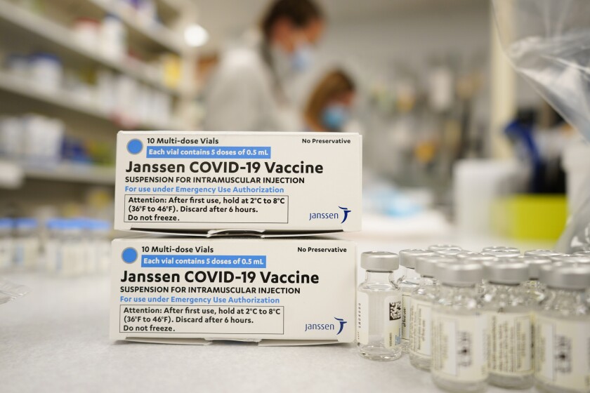 Boxes stand next vials of Johnson & Johnson COVID-19 vaccine.