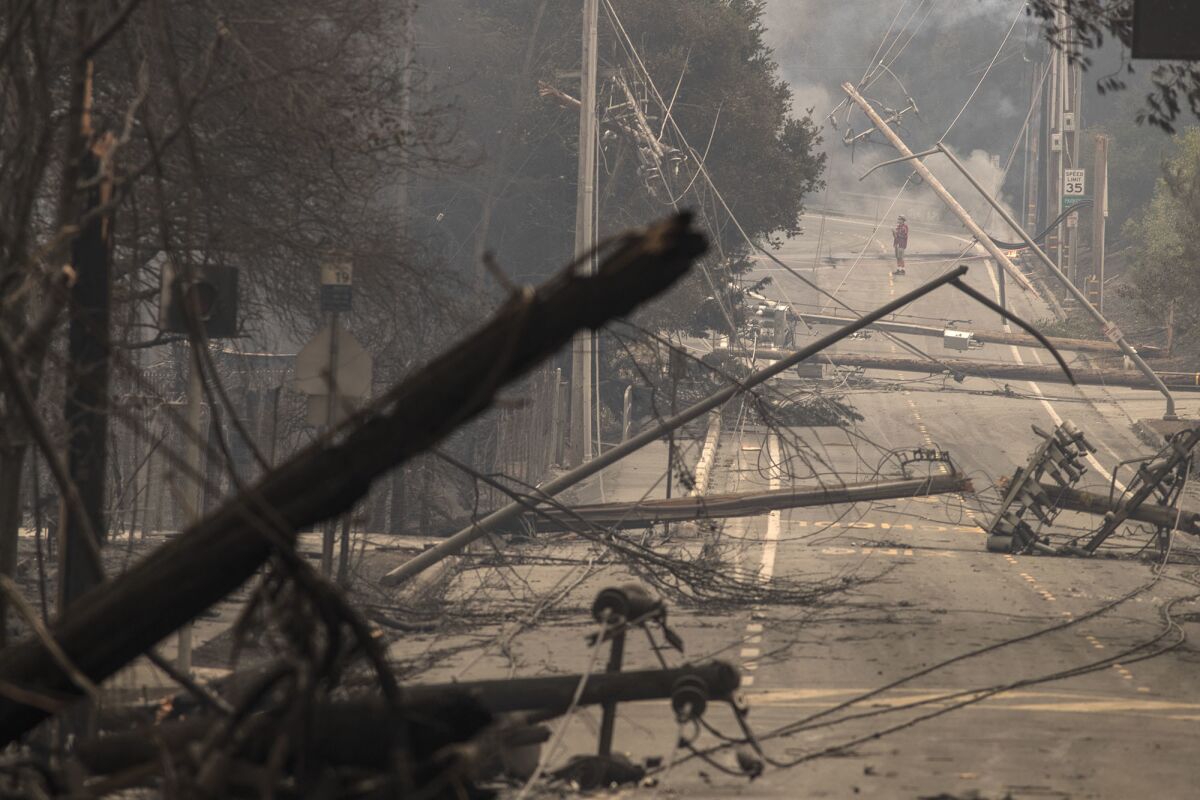 Downed power poles and lines block a street in the Hidden Valley neighborhood in Santa Rosa