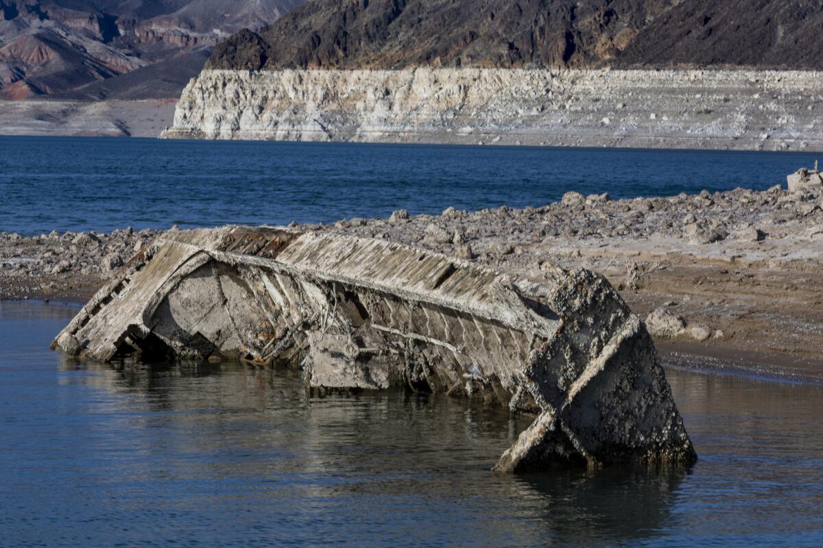 A dilapidated boat listing on its side in shallow water on the shores of Lake Mead
