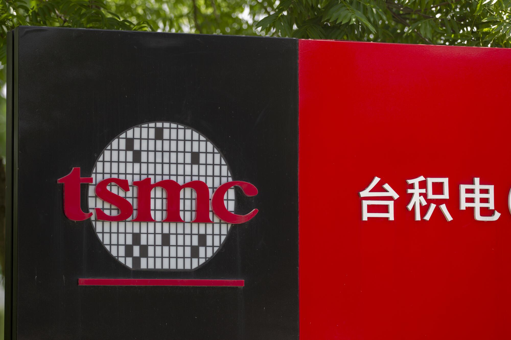 A sign with a company logo with the lowercase letters t-s-m-c next to white Chinese characters on a red background