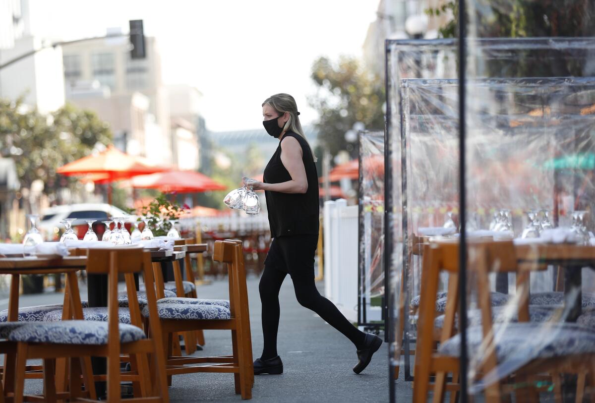 An employee prepares outdoor tables at a restaurant Fifth Avenue in San Diego.