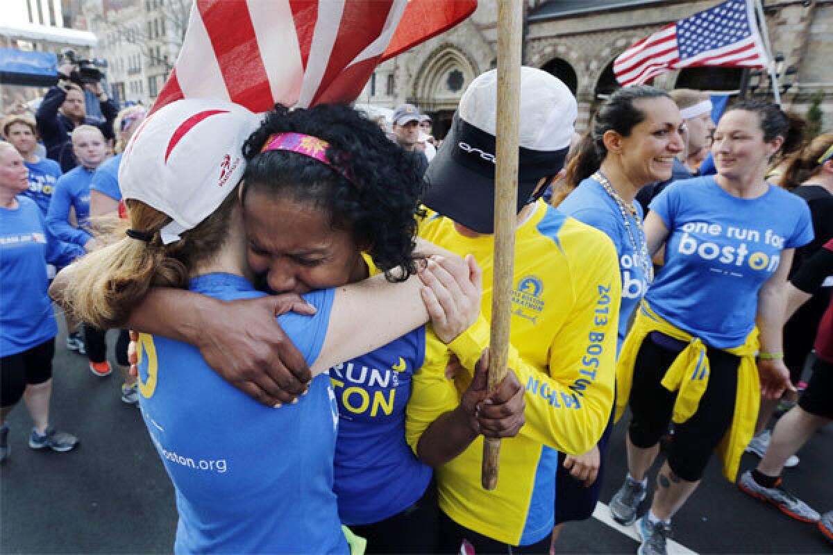 Rosa Evora, center, hugs a fellow participant in a cross-country relay that began in March in California and ended at the Boston Marathon finish line Sunday.