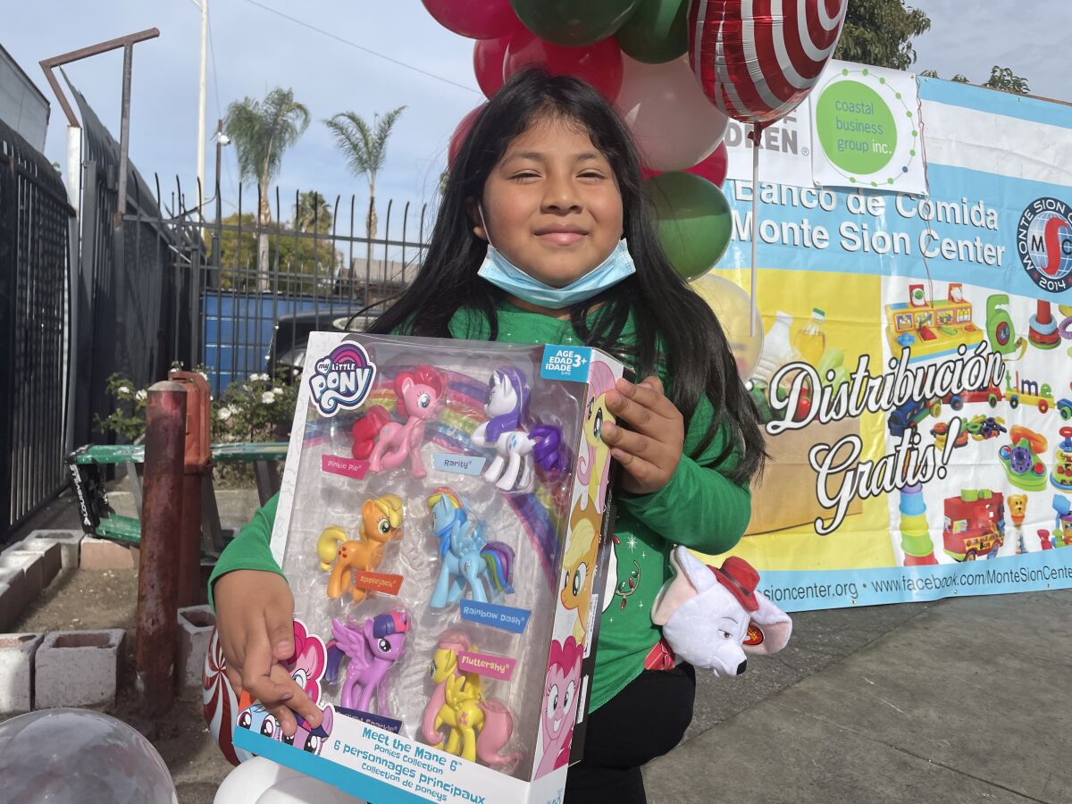 Una niña muestra el regalo que recibió en la distribución de juguetes navideños en el Este de Los Ángeles.