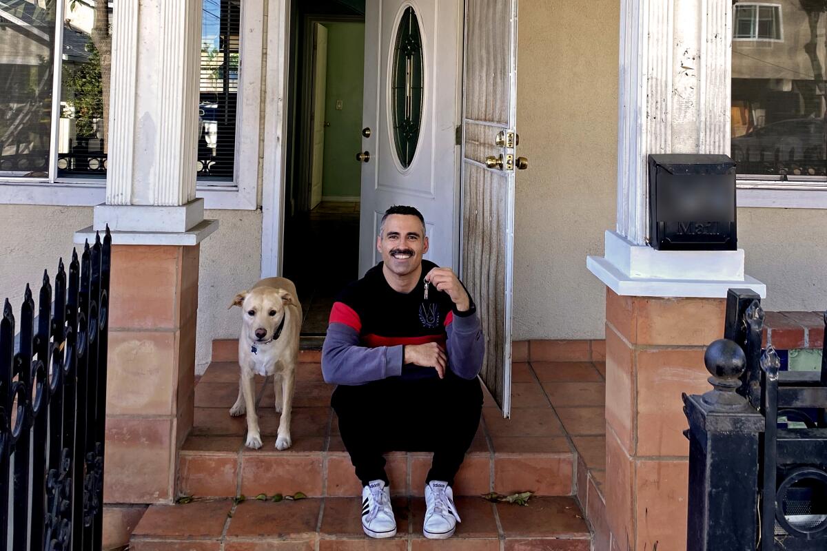 Alex Mohajer and his dog sit on the porch of the house he bought in Long Beach 