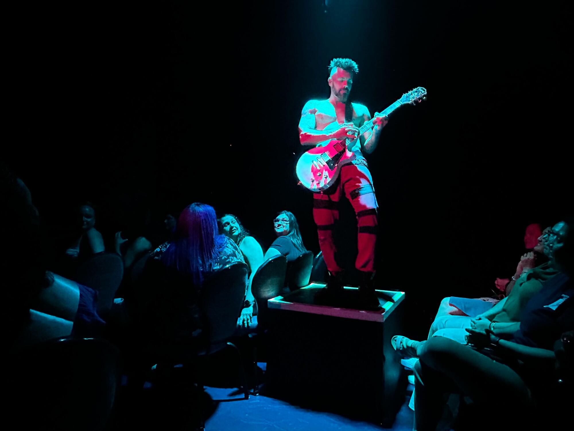 A male dancer performs with a guitar.