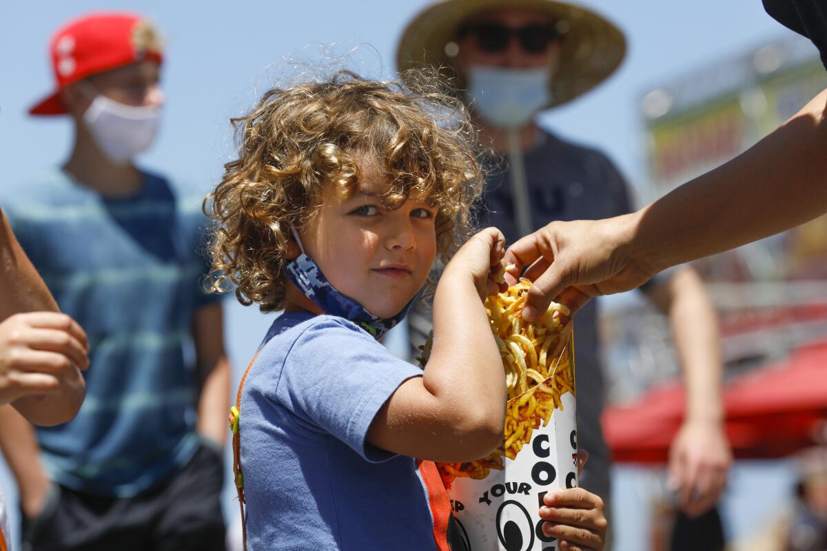 Owen Jana, 5, of Del Mar holds on tight to an oversized serving of curly fries on opening day for HomeGrownFun on Friday.