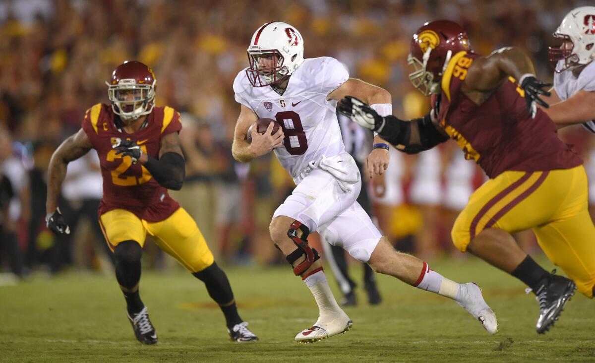 Stanford quarterback Kevin Hogan runs between USC linebacker Su'a Cravens, left, and defensive tackle Antwaun Woods during a game on Sept. 19. Stanford beat USC, 41-31.