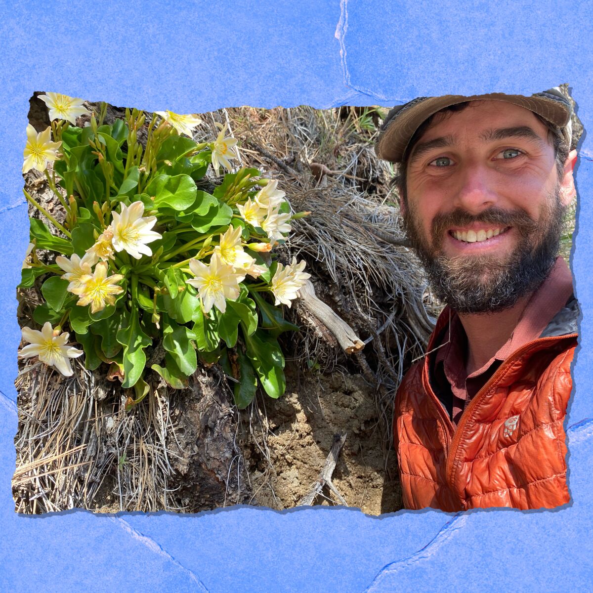 A man with a beard smiles as he poses for a photo beside a plant with yellow and white flowers.