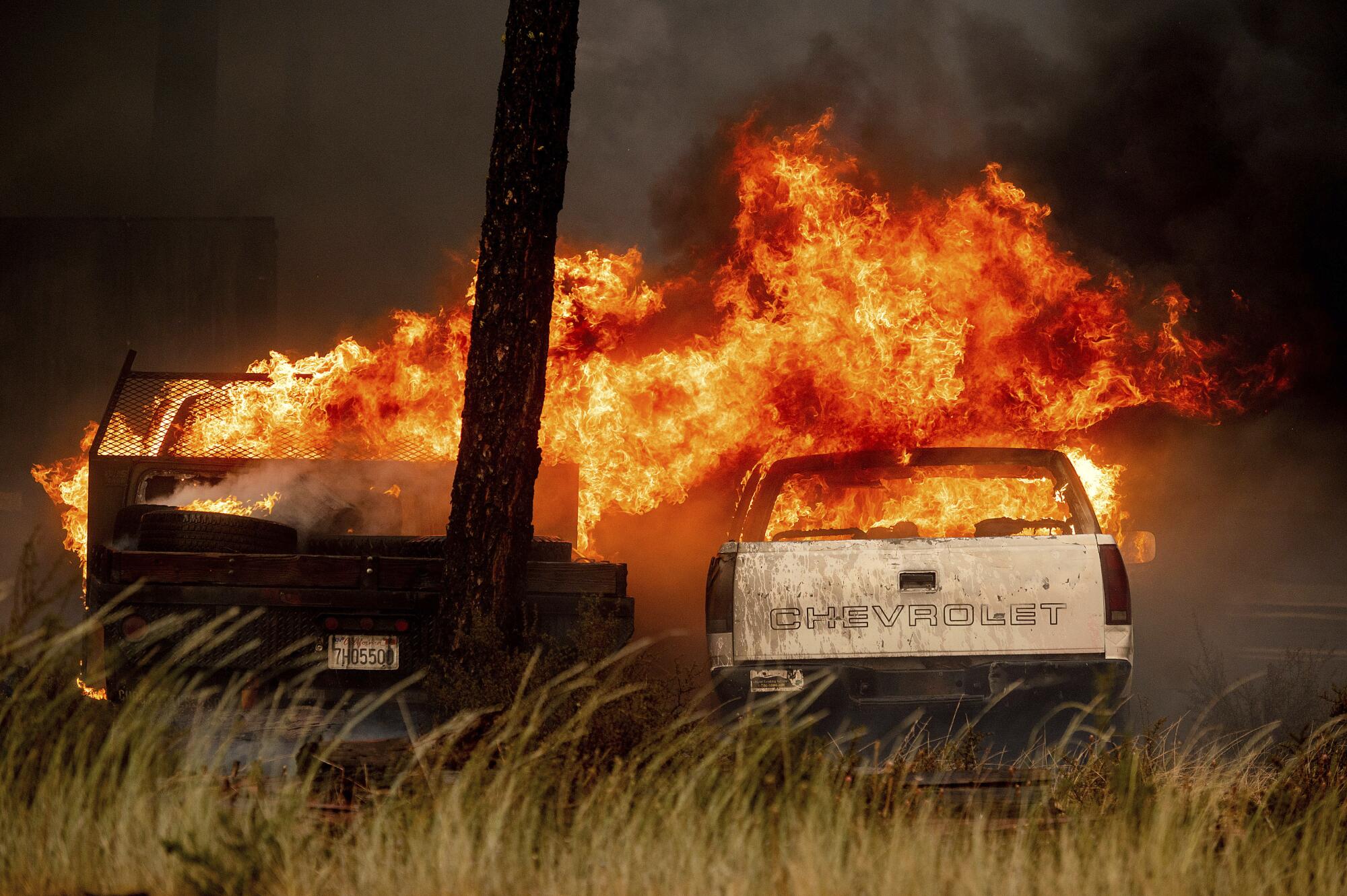 Wind drives flames from one vehicle to another in a wrecking yard in Chester, Calif.