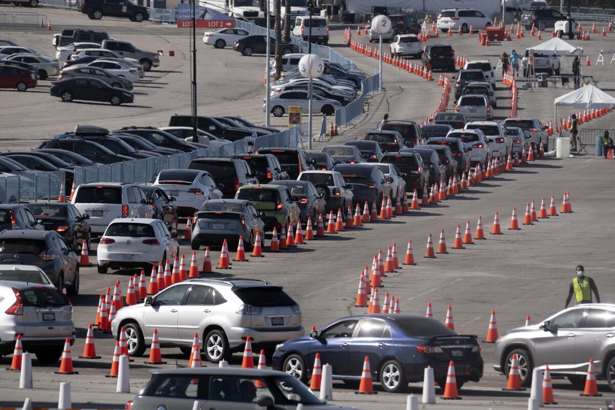 Múltiples automóviles hacen fila para ingresar a un sitio de vacunación contra el COVID-19 en el Dodger Stadium