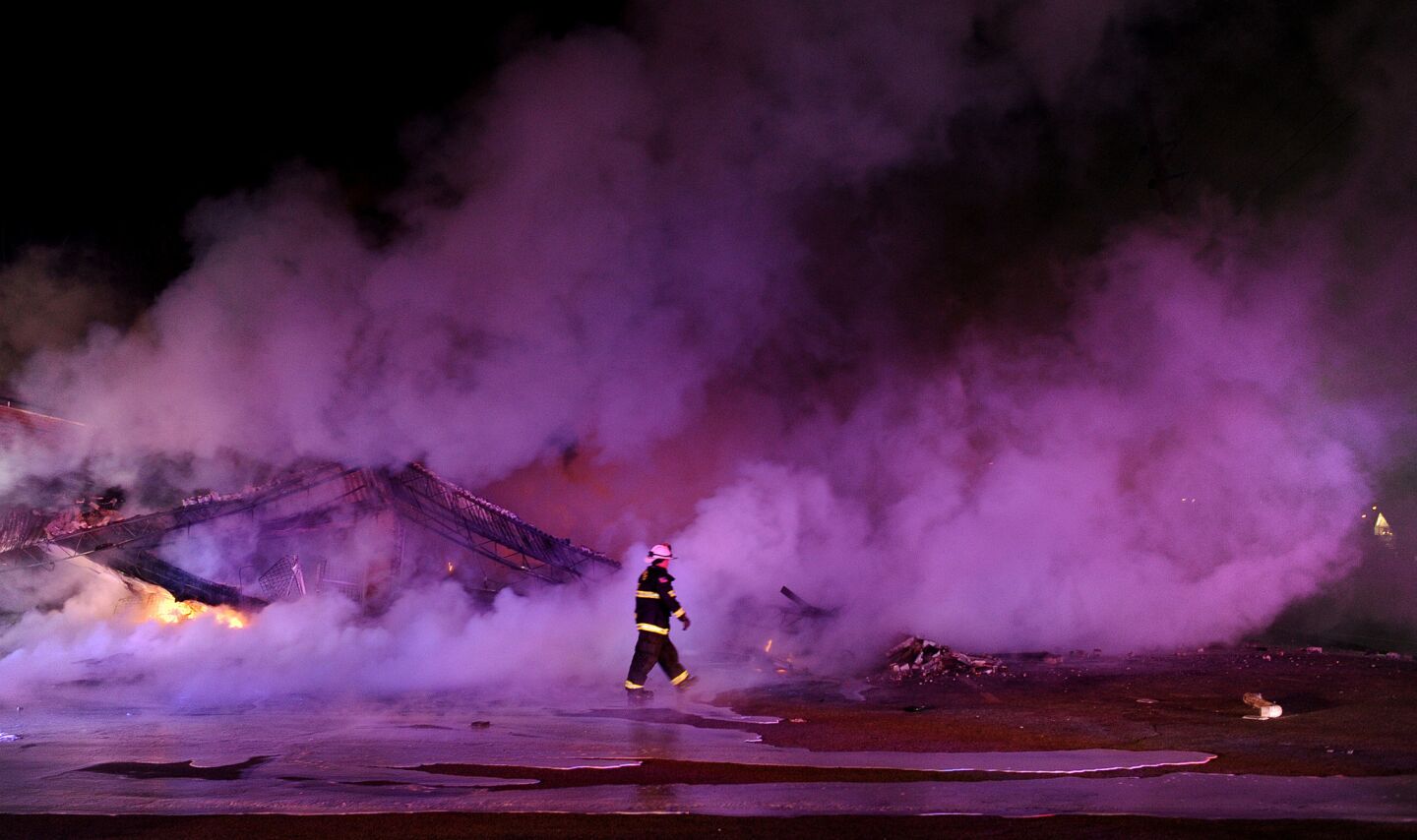 A firefighter walks by a burned strip mall at Chambers Road and West Florissant Avenue after a grand jury decision in Ferguson, Mo.