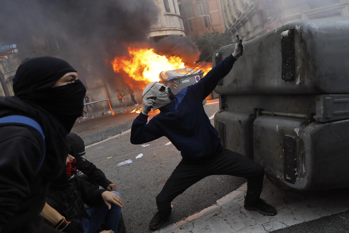 A protester uses a slingshot during clashes with police in Barcelona, Spain
