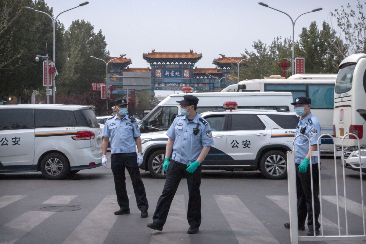 Police stand guard outside the Xinfadi wholesale food market district in Beijing.