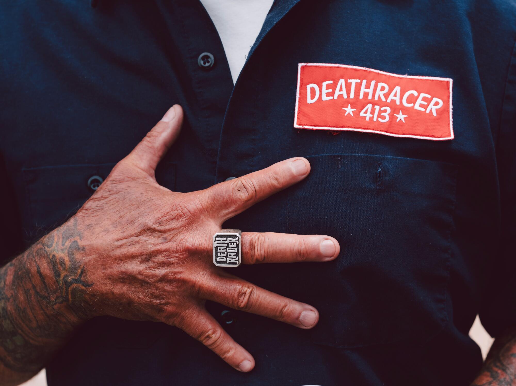 A close up of a man's ring and shirt patch bearing the Deathracer413 name.
