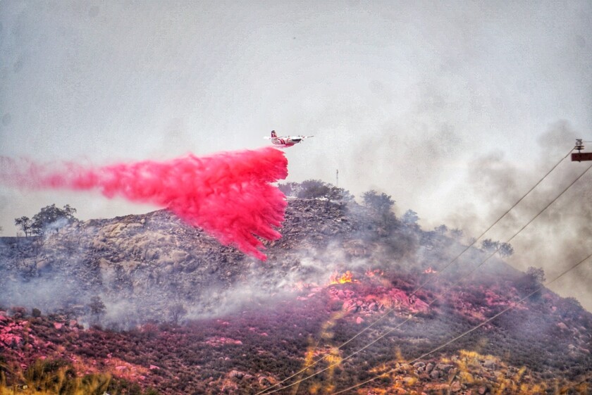 A firefighting plane drops fire retardant on the hillsides north of Rancho Ballena Lane about 3:18 p.m. Wednesday. 