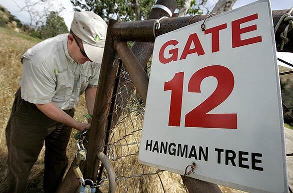 Dave Raetz unlocks a gate within the Irvine Ranch Conservancy, which offers docent-led hikes to the Hangman's Tree monument.