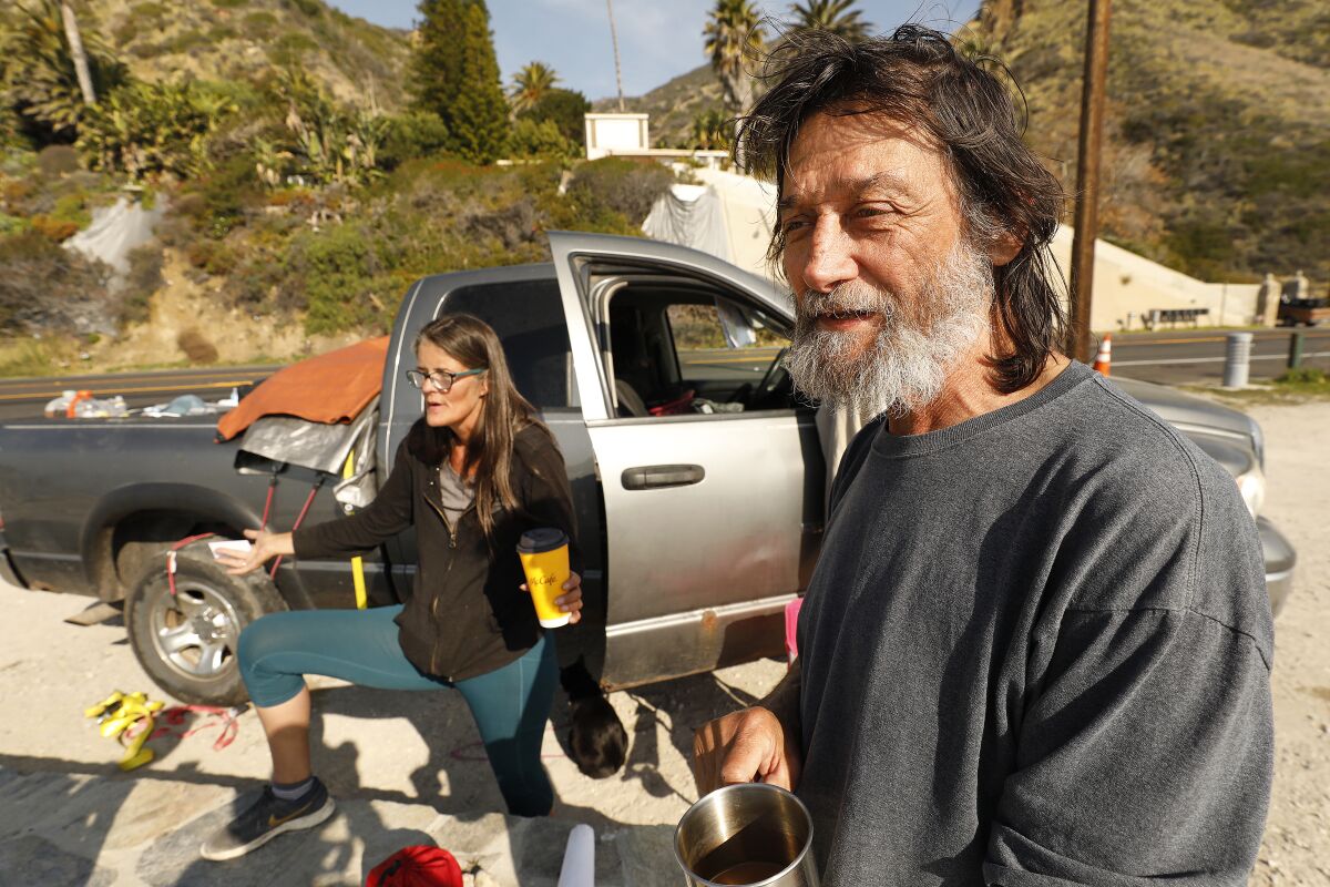 Elizabeth Dobbs and Anthony Augustyniak take in the view outside their vehicle where they live parked along Pacific Coast Highway at Las Tunas County Beach.
