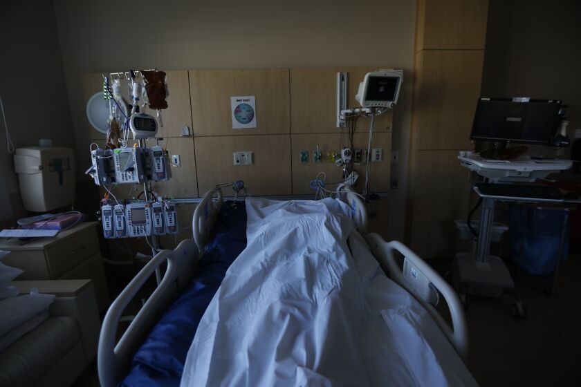A white bag containing a deceased COVID patient sits in a hospital room