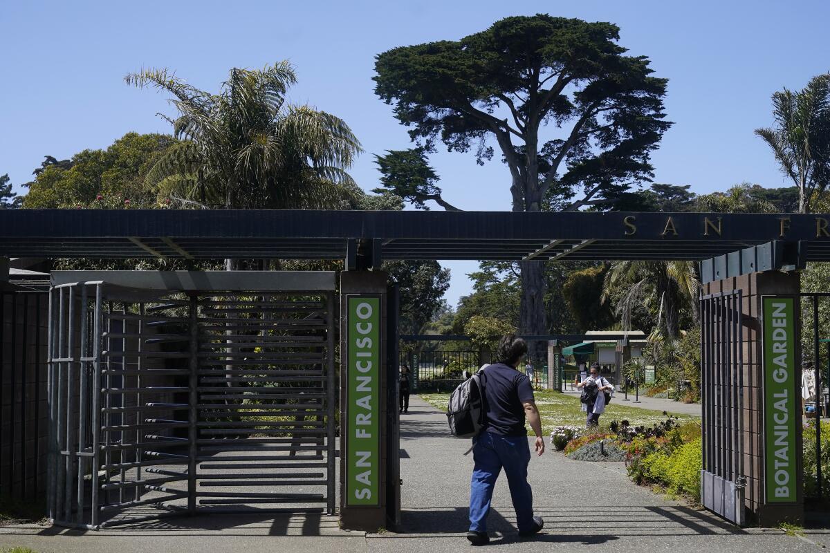 A person walks through the entrance to a botanical garden