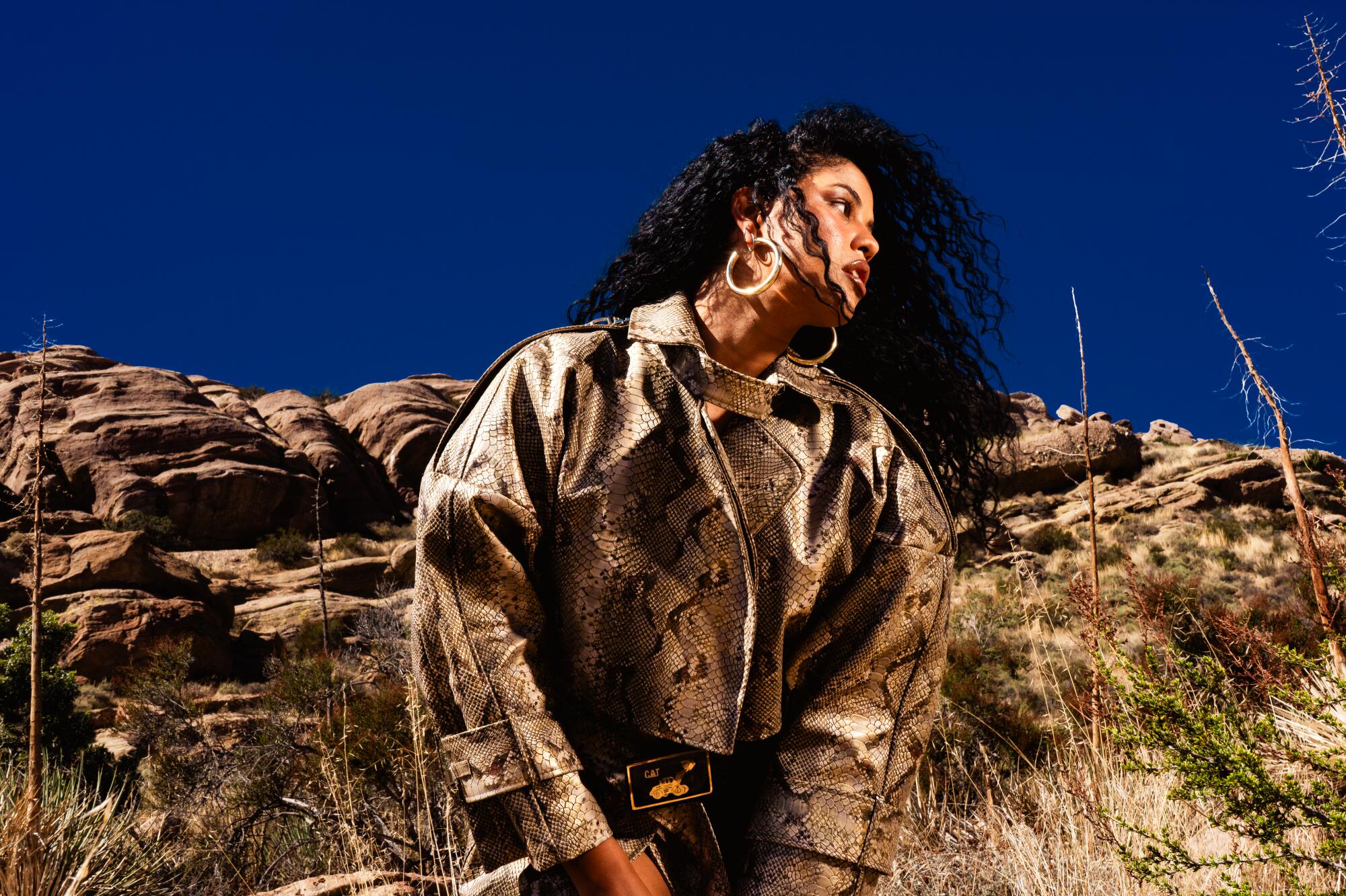 Yendry poses in a snake skin jacket in the desert.