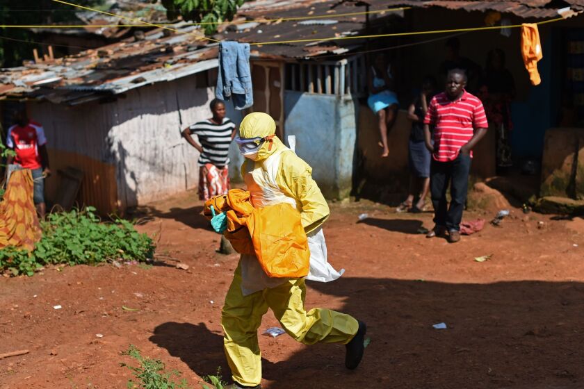 A member of a Red Cross burial team carries the body of a child believed to have died of Ebola in the Sierra Leone capital, Freetown, in November.