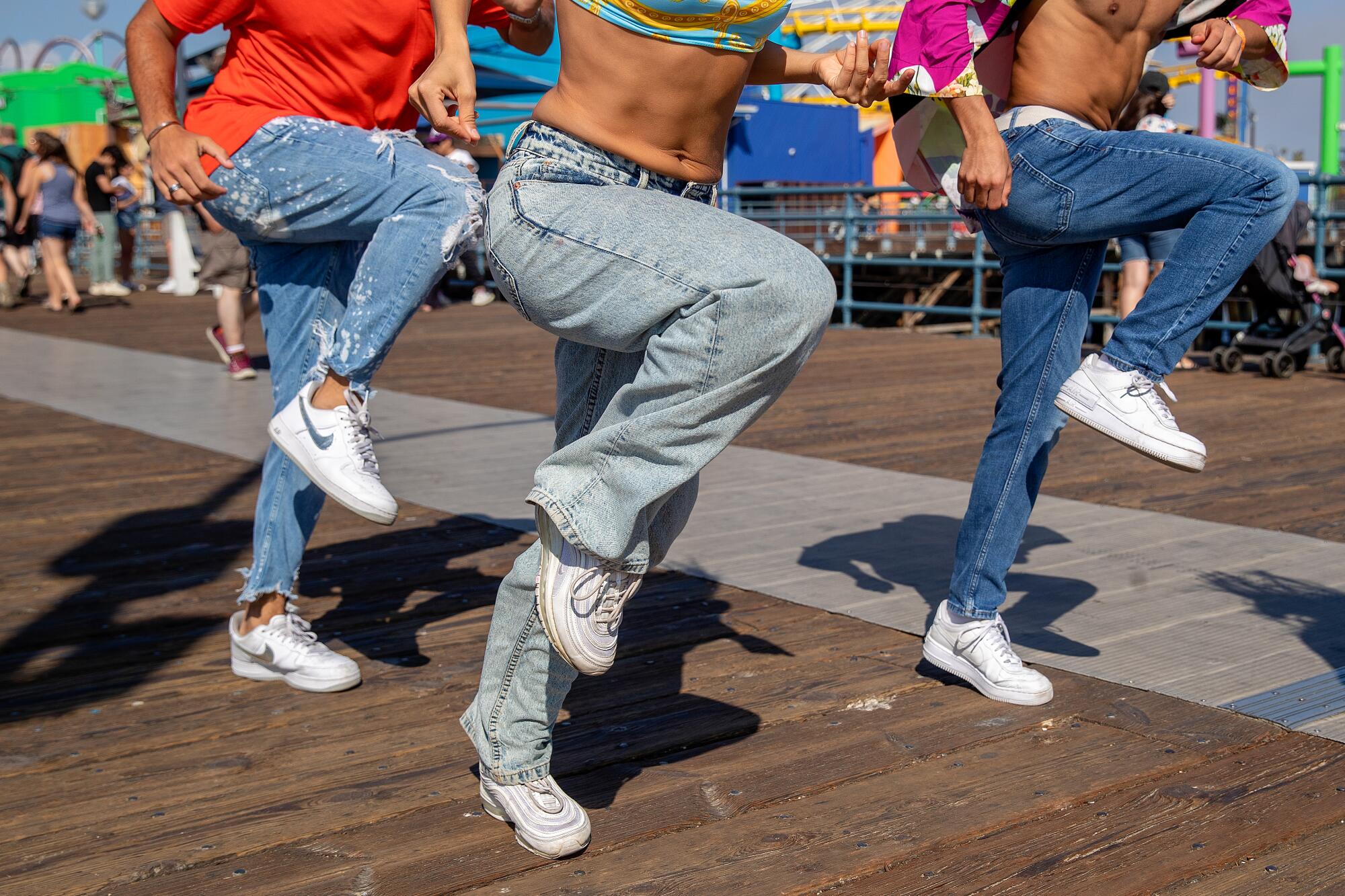 A detail image of three pairs of legs dancing on a pier.
