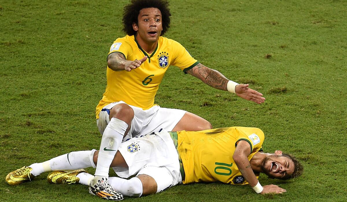 Brazil forward Neymar is on the ground in pain as teammate Marcelo shouts to the sideline for assistance after the star striker took a knee to his back late in the game against Colombia on Friday at the World Cup.