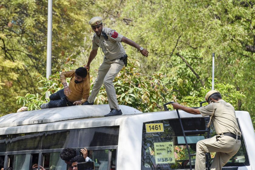 A policeman drags a supporter of opposition Congress party atop a police vehicle as they are detained while protesting against their leader Rahul Gandhi's expulsion from Parliament in New Delhi, India, Monday, March 27, 2023. Gandhi was expelled from Parliament a day after a court convicted him of defamation and sentenced him to two years in prison for mocking the surname Modi in an election speech. (AP Photo/Deepanshu Aggarwal