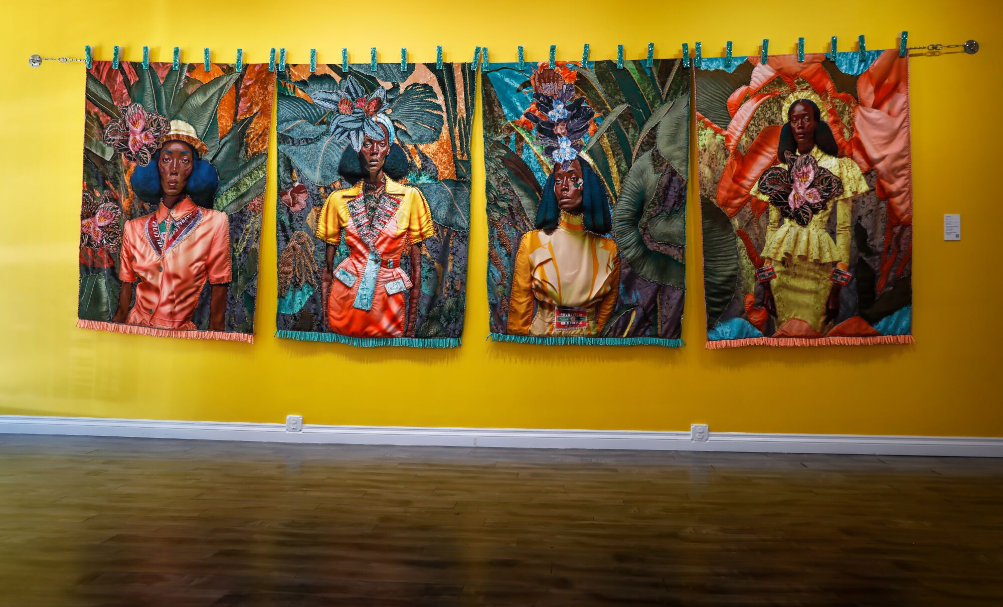 A series of four tapestries on a yellow wall.