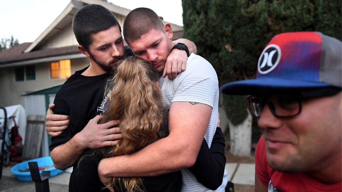 Dylan McNey, hugs Colby Kalisek and Justin Veditz, all survivors of the Bordeline Bar & Grill shooting, during a meeting at a home of a fellow survivor in Thousand Oaks.
