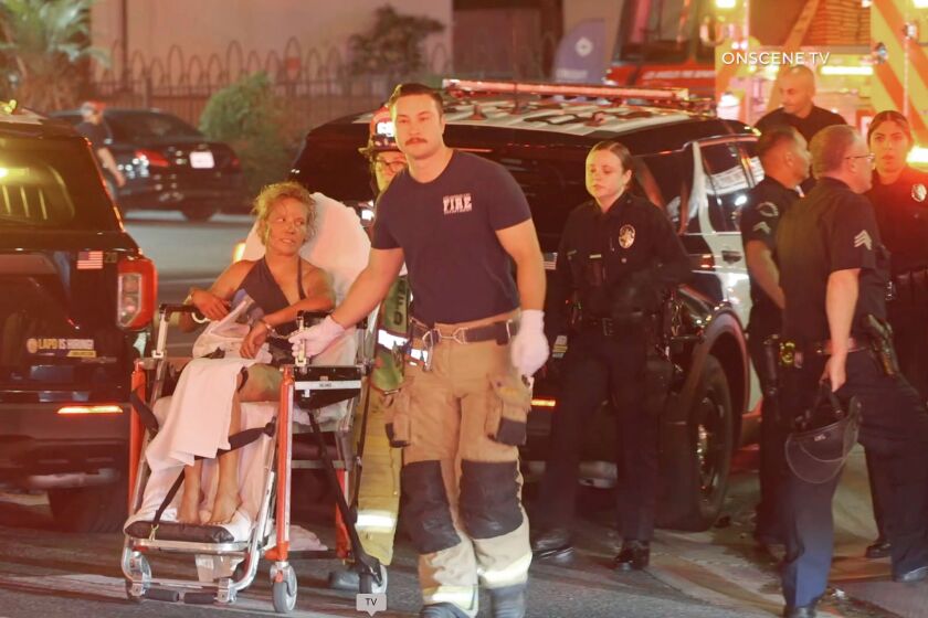 A woman is in custody after barricading herself inside a 7-Eleven store that eventually caught fire in the Mid-Wilshire neighborhood of Los Angeles Monday night.