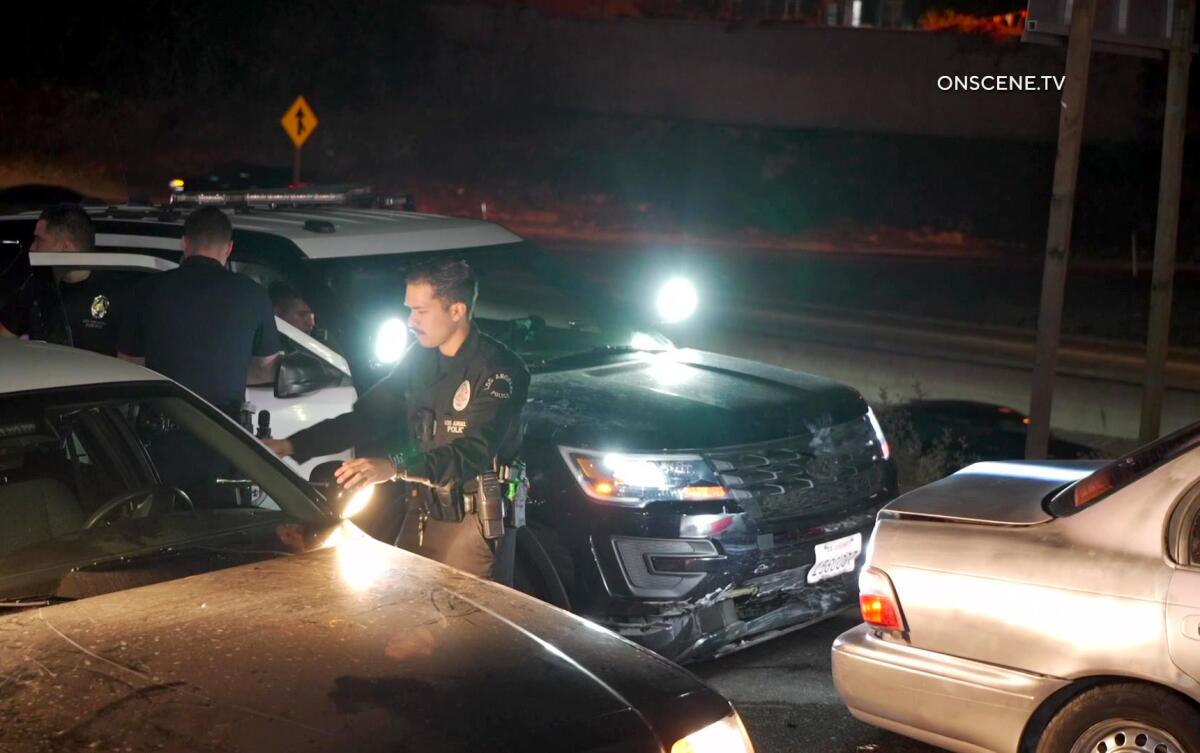 Officers in and around a police vehicle shining lights on other cars