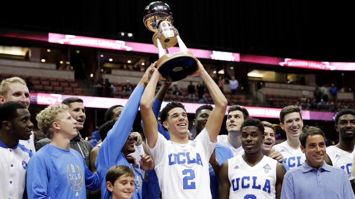 Lonzo Ball hoists the Wooden Legacy Trophy while posing for photos with teammates after UCLA defeatd Texas A&M in the championship game Sunday.