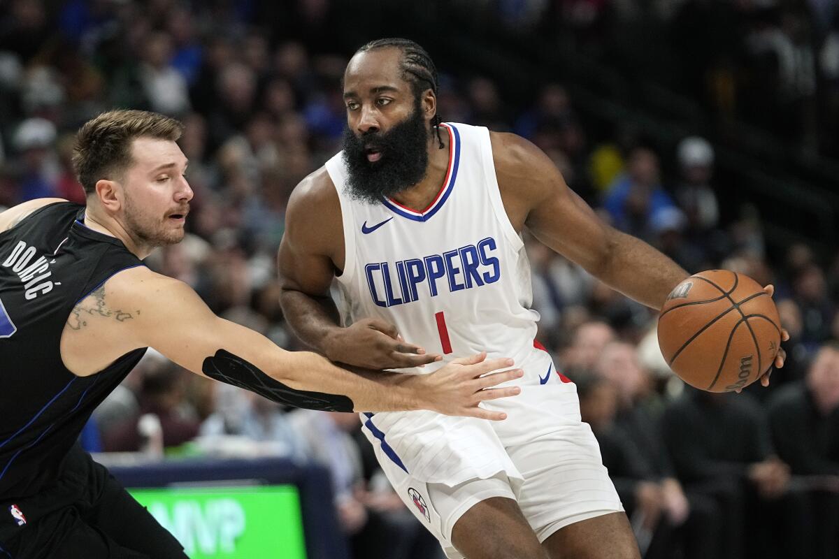 Clippers guard James Harden tries to dribble past Mavericks guard Luka Doncic, who reaches for the ball.