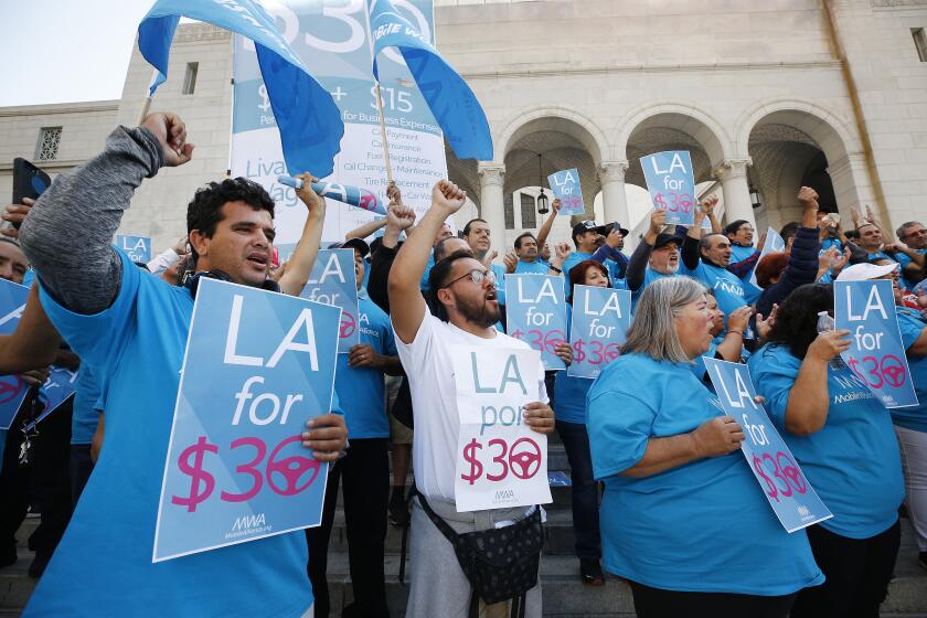 LOS ANGELES, CA - OCTOBER 15, 2019 Uber driver Joel Carbonell, left, and Lyft driver Eduardo Belalcazar, right, with Mobile Workers Alliance cheer on the Spring Street steps of Los Angeles City Hall as the drivers rally to support a City Council proposal to guarantee a $30-per-hour wage for drivers. (Al Seib / Los Angeles Times)