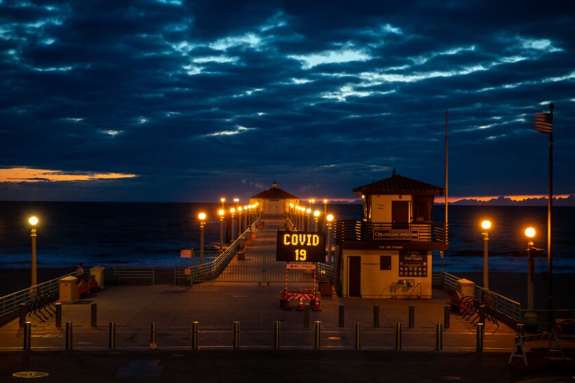 MANHATTAN BEACH, CA --MARCH 25, 2020 -The Manhattan Beach, CA, Pier is gated and locked and a city maintenance sign repeats the message that (parking) "LOT CLOSED," "COVID 19" and "Social Distancing," the evening of March 25, 2020. (Jay L. Clendenin / Los Angeles Times)