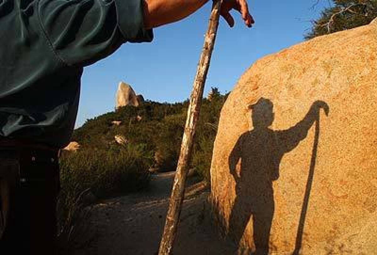 A hiker and his walking stick frame a 15-foot boulder along Bear Canyon Loop Trail in Cleveland National Forest.