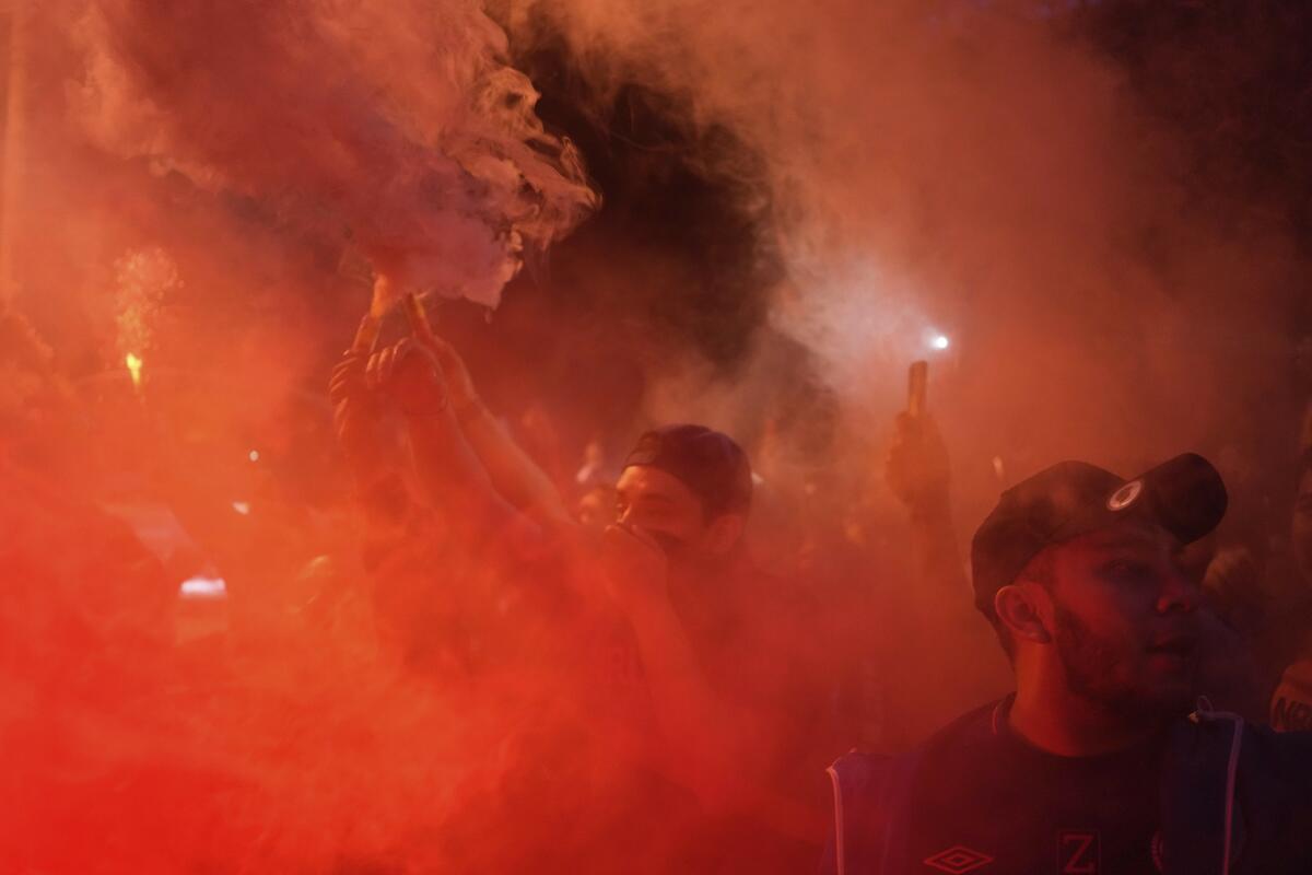 Fans of Guatemala's Municipal hold flares and cheer after clashing with fans of Honduras' Olimpia outside Doroteo Guamuch stadium, before a CONCACAF League soccer match in Guatemala City, Thursday, Aug. 18, 2022. (AP Photo/Moises Castillo)