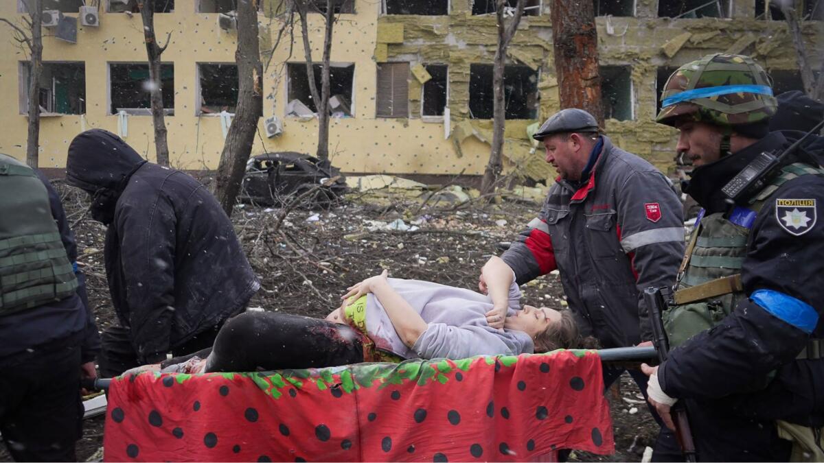 A woman is carried on a stretcher outside what looks like a bombed-out building in "20 Days in Mariupol."