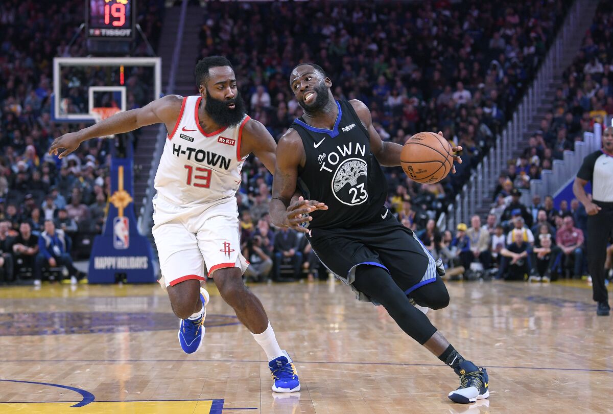 Warriors forward Draymond Green tries to drive past Rockets guard James Harden during an NBA game on Dec. 25, 2019, in San Francisco.