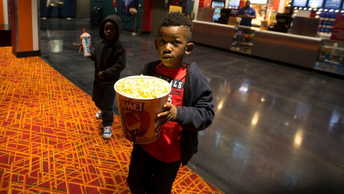 Pa-Den Cotton, holding popcorn, and his brother Jekhi get snacks before seeing a movie at 24:1 Cinema.