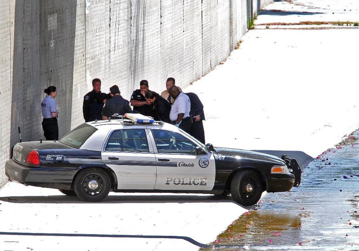 Glendale Police and Los Angeles County Coroner officials investigate the scene where a body was found near Glorietta Park inside a suitcase that was dumped in the wash that runs through the park, under the Glorietta Avenue Bridge in Glendale.