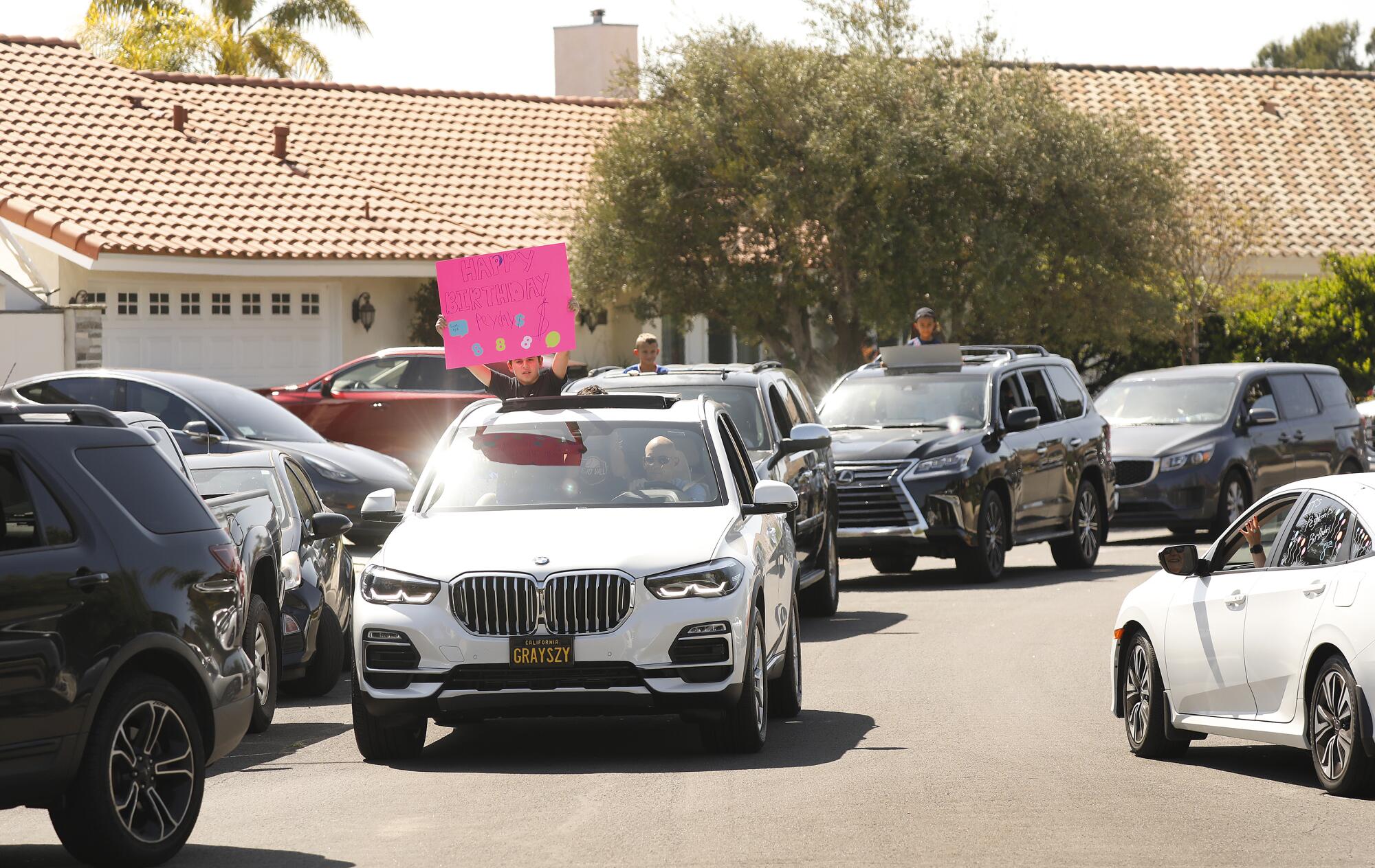 Vehicles filled with cheering parents and teammates fill a cul de sac to celebrate Peyton's 8th birthday near his home in Thousand Oaks.