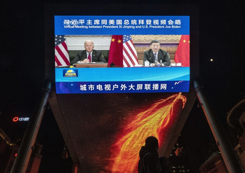 Un grand écran affiche le président Biden et le président chinois Xi Jinping lors d'un sommet virtuel