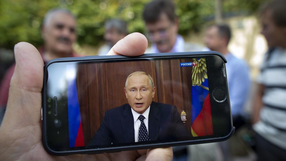 A man on a Moscow street watches President Vladimir Putin address the nation on a smartphone.
