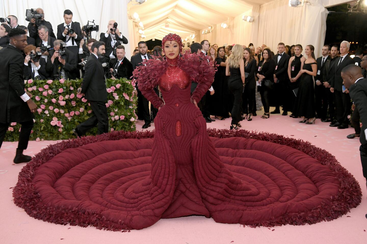 Cardi B arrives in a custom oxblood-colored Thom Browne gown with a bedazzled swim cap-style headpiece.