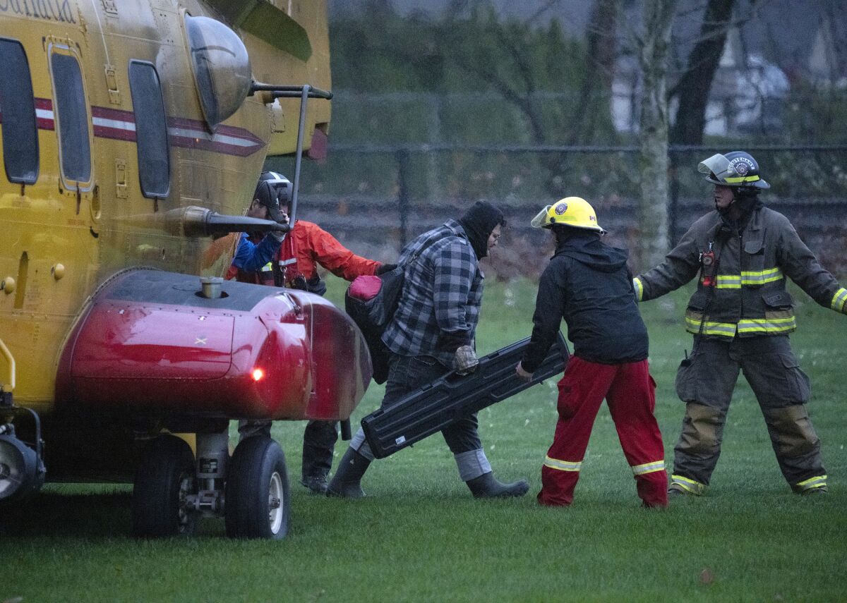 Search and rescue personnel help flood evacuees disembark from a helicopter in Agassiz, British Columbia, Monday, Nov. 15, 2021. (Jonathan Hayward/The Canadian Press via AP)