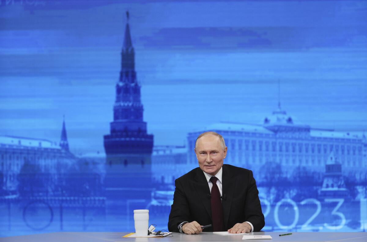 Vladimir Putin speaks in front of a backdrop.