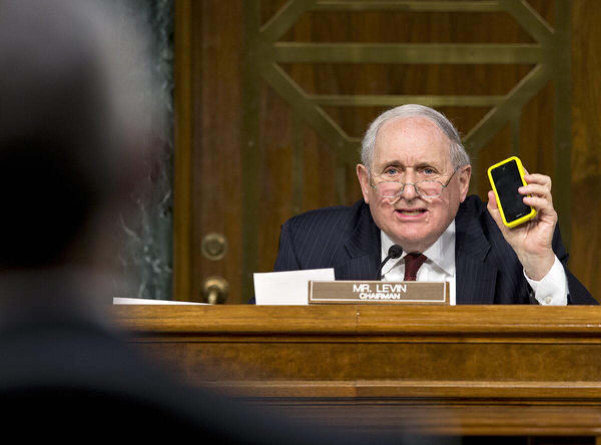 Sen. Carl Levin (D-Mich.) holds up his iPhone as he tells Apple Chief Executive Tim Cook, "We love the iPhone and the iPad."