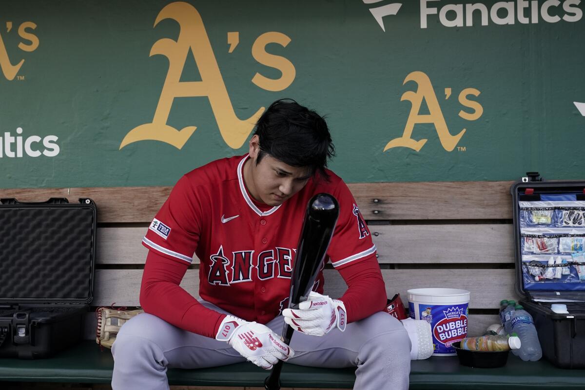 Angels star Shohei Ohtani sits in the dugout before the team's loss to the Oakland Athletics.